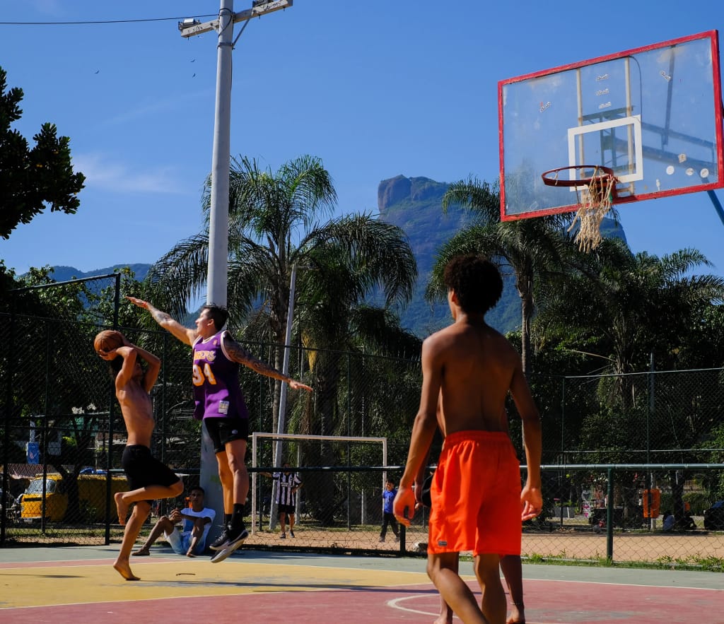 Dois jovens jogando basquete em quadra ao ar livre