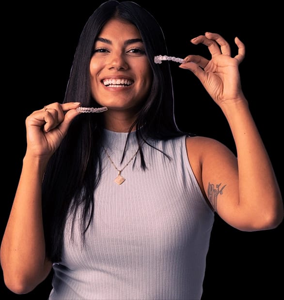 Mulher sorridente segurando dois alinhadores dentais transparentes