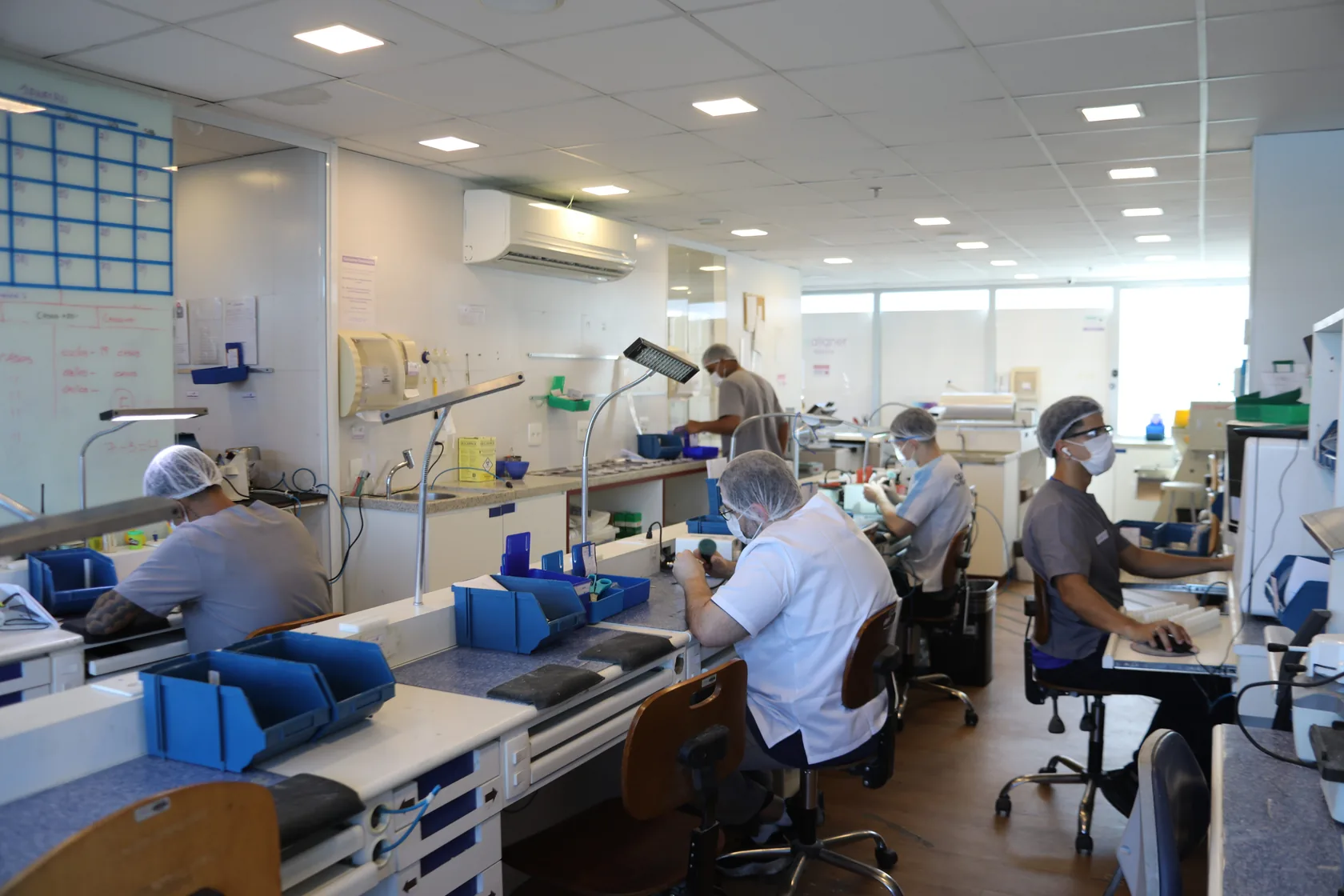 Salão de produção da fábrica da ezaligner, com a equipe nas bancadas